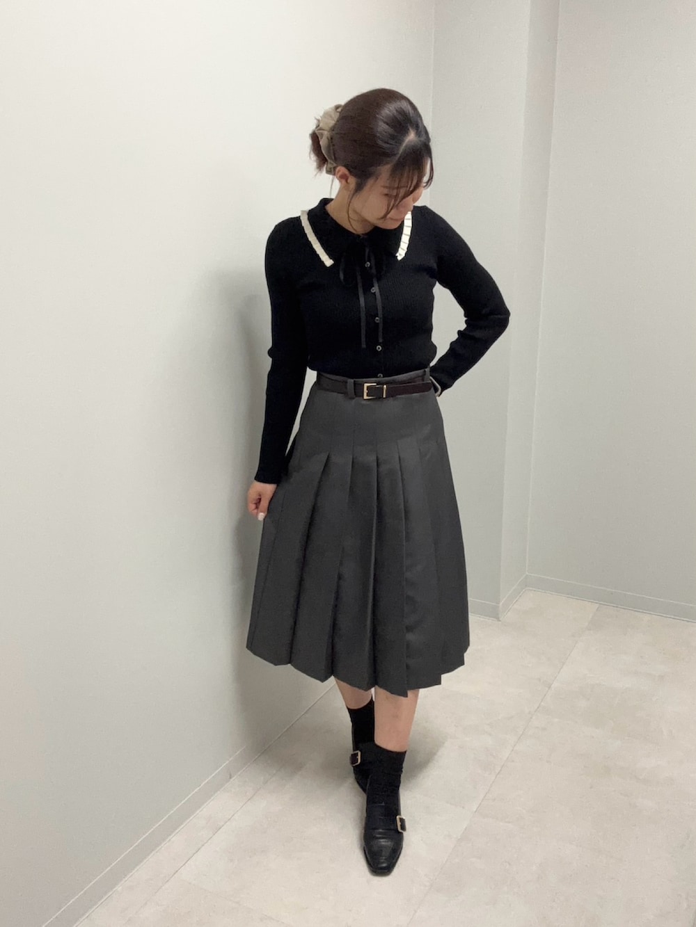 ブラック系のニット/セーター、グレー系のスカートを着用したレディースの春コーディネートの2枚目の写真