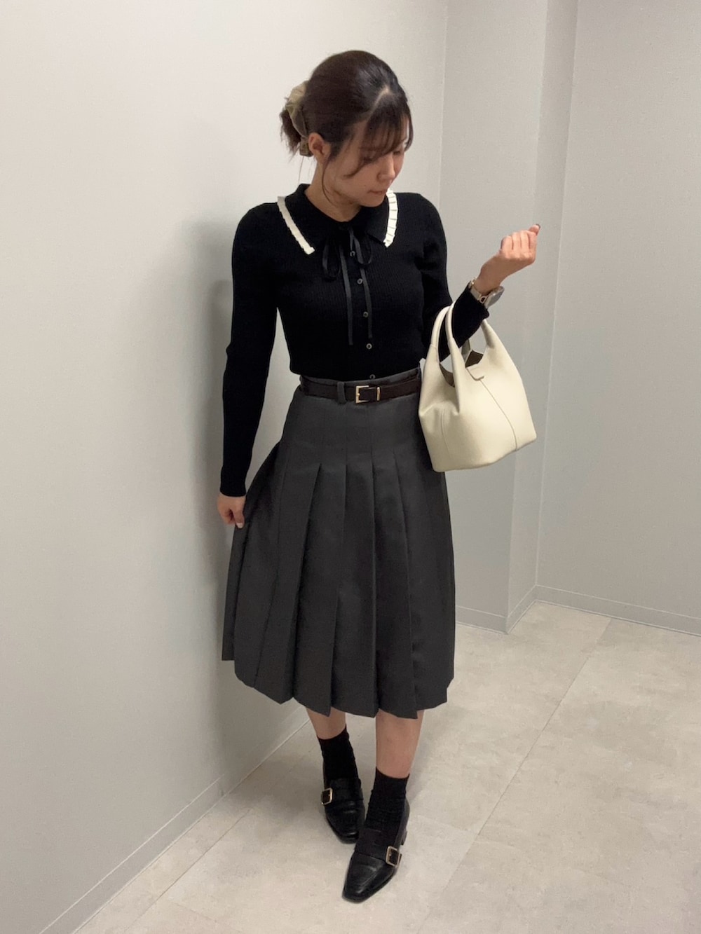 ブラック系のニット/セーター、グレー系のスカートを着用したレディースの春コーディネートの3枚目の写真