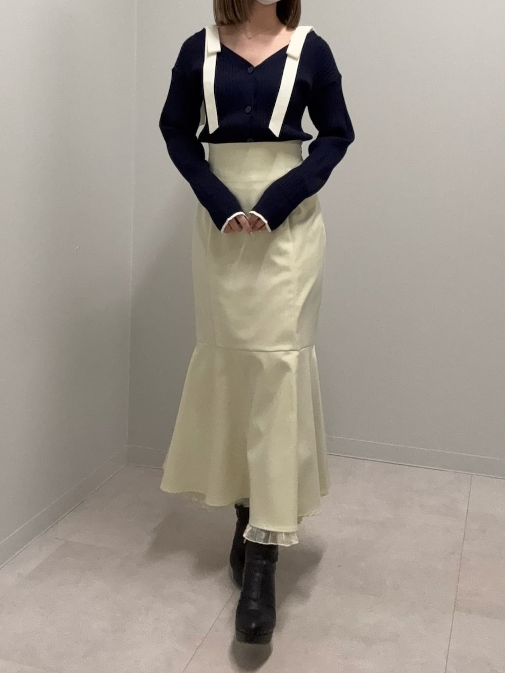 ブルー系のニット/セーター、イエロー系のスカート、ブラック系のブーツを着用したレディースの春コーディネートの2枚目の写真