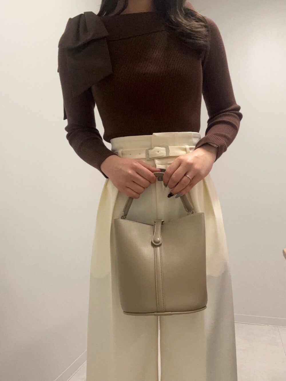 ブラウン系のニット/セーター、ホワイト系のその他パンツ、ベージュ系のショルダーバッグを着用したレディースの春コーディネートの4枚目の写真