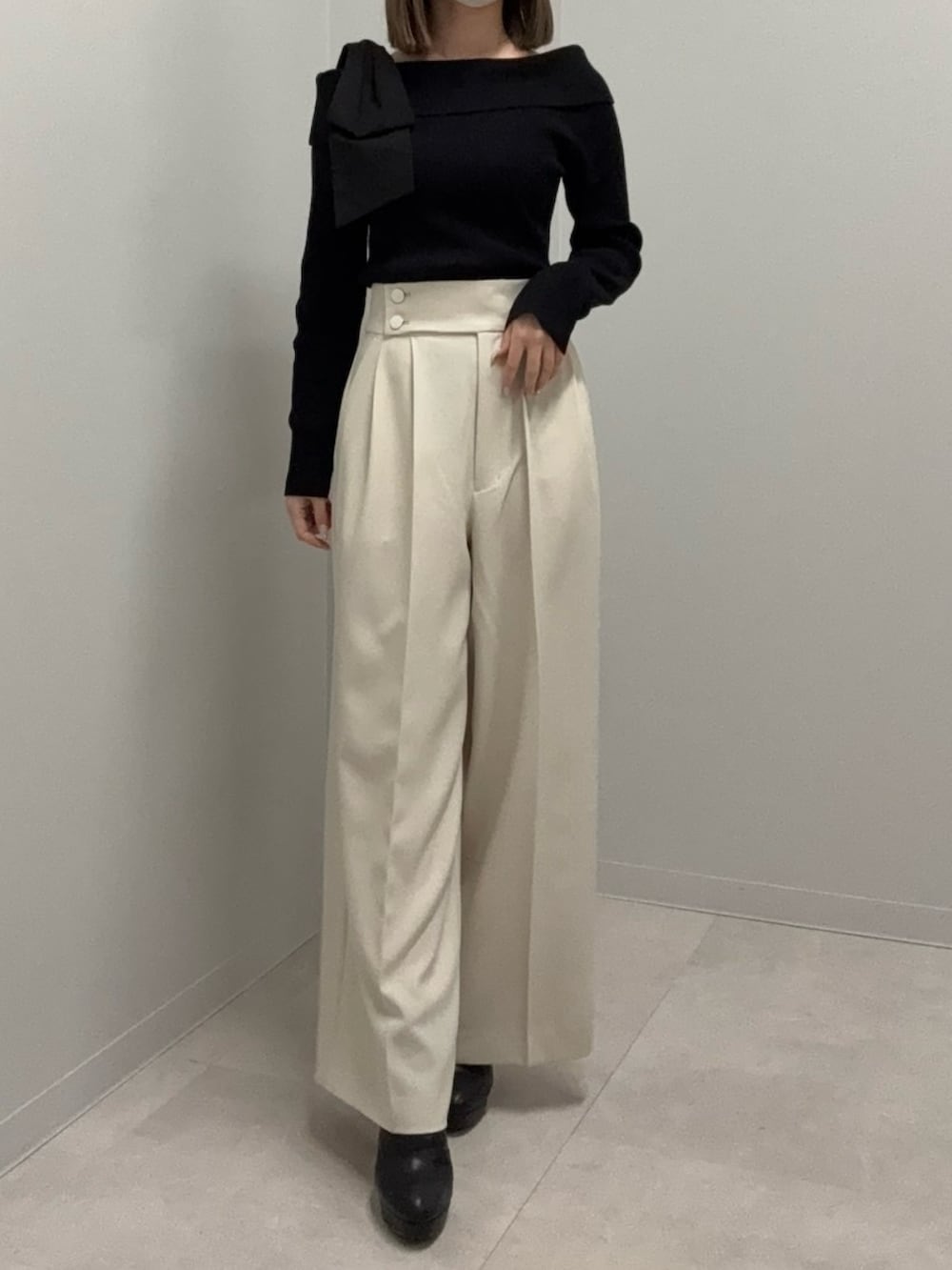 ブラック系のニット/セーター、ベージュ系のその他パンツ、ブラック系のブーツを着用したレディースの春コーディネートの2枚目の写真