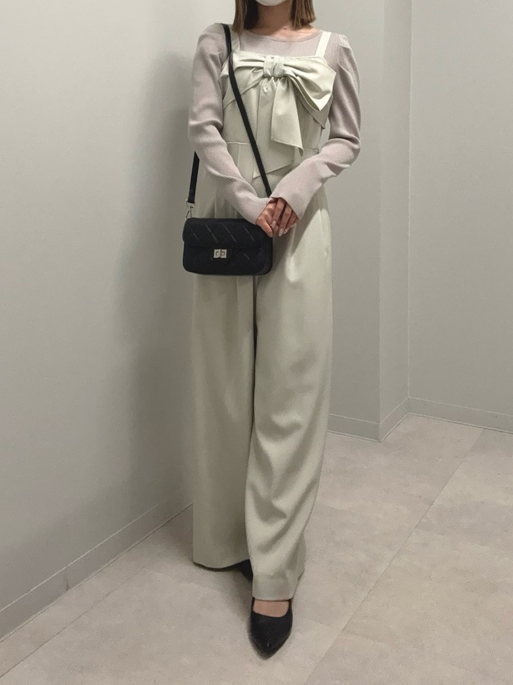 グレー系のニット/セーター、ベージュ系のつなぎ/オールインワン、ブラック系のショルダーバッグを着用したレディースの春コーディネートの2枚目の写真