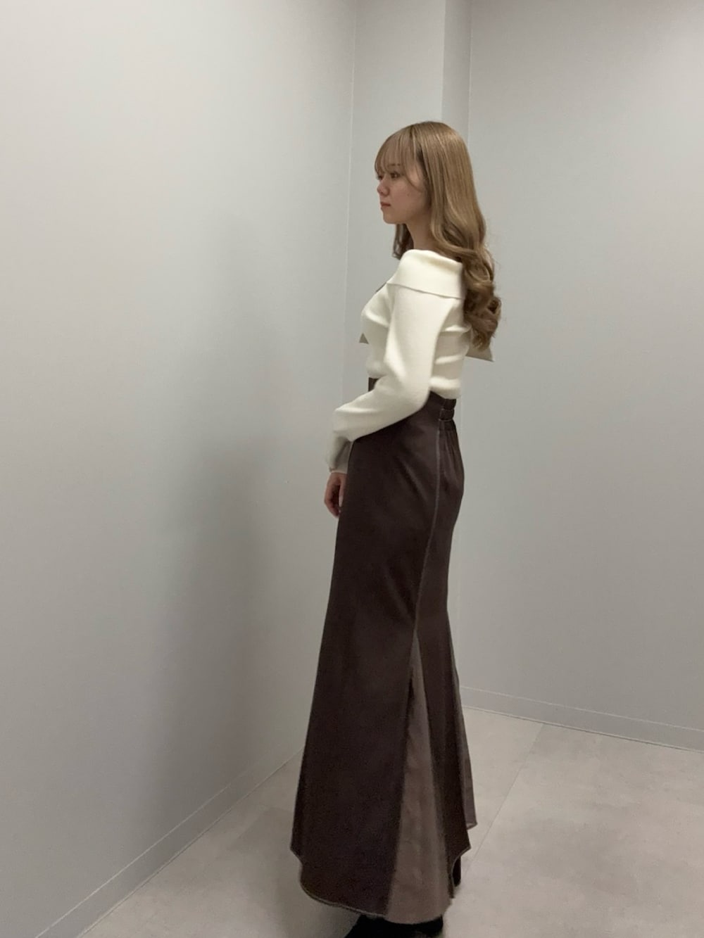 ホワイト系のニット/セーター、ブラウン系のスカートを着用したレディースの冬コーディネートの2枚目の写真