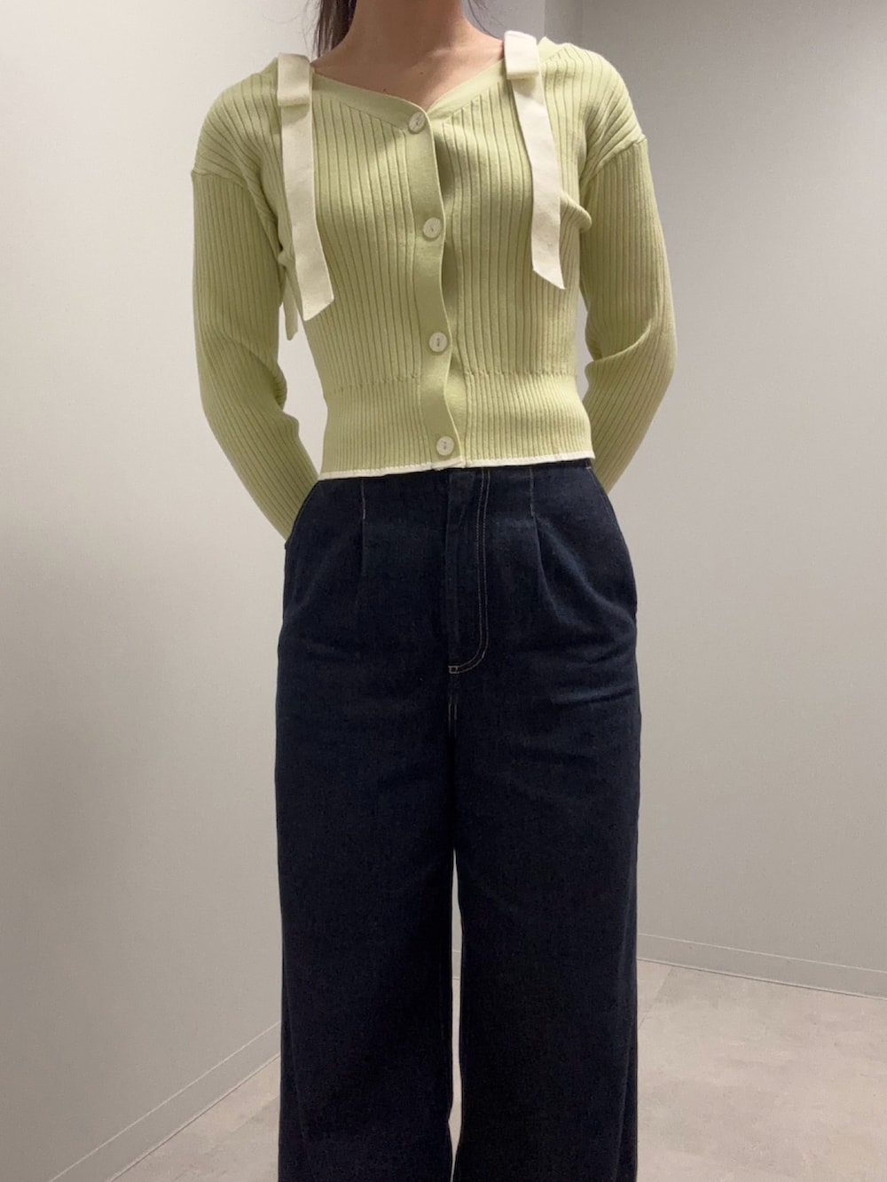 グリーン系のニット/セーター、ブルー系のデニムパンツを着用したレディースの春コーディネートの2枚目の写真