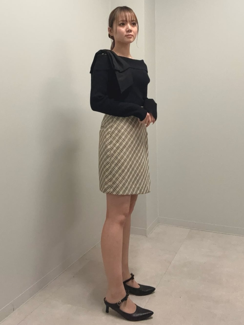 ブラック系のニット/セーター、ベージュ系のスカート、ブラック系のパンプスを着用したレディースの春コーディネートの2枚目の写真