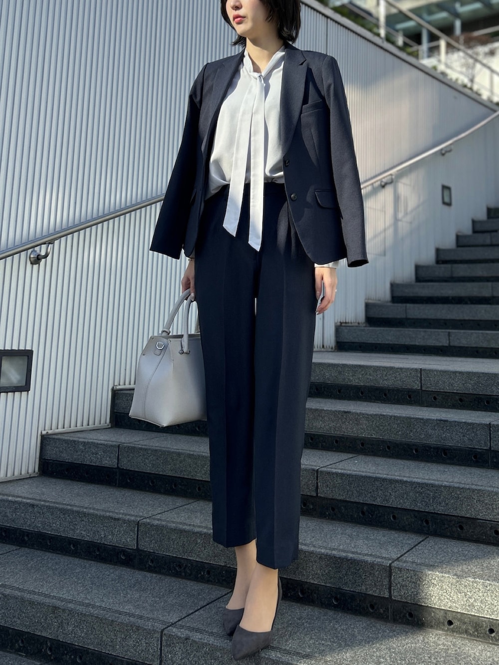 グレー系のシャツ/ブラウス、ブルー系のスーツパンツ、ブルー系のスーツジャケットを着用したレディースの春コーディネートの2枚目の写真