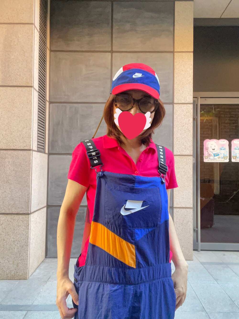 レッド系のポロシャツ、ブルー系のつなぎ/オールインワン、ベージュ系のレインシューズを着用したレディースの秋コーディネートの2枚目の写真