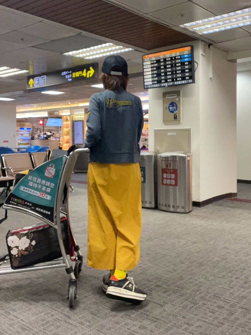 グレー系のスタジャン、イエロー系のジャンパースカート、ブラック系のスニーカーを着用したレディースの夏コーディネートの2枚目の写真