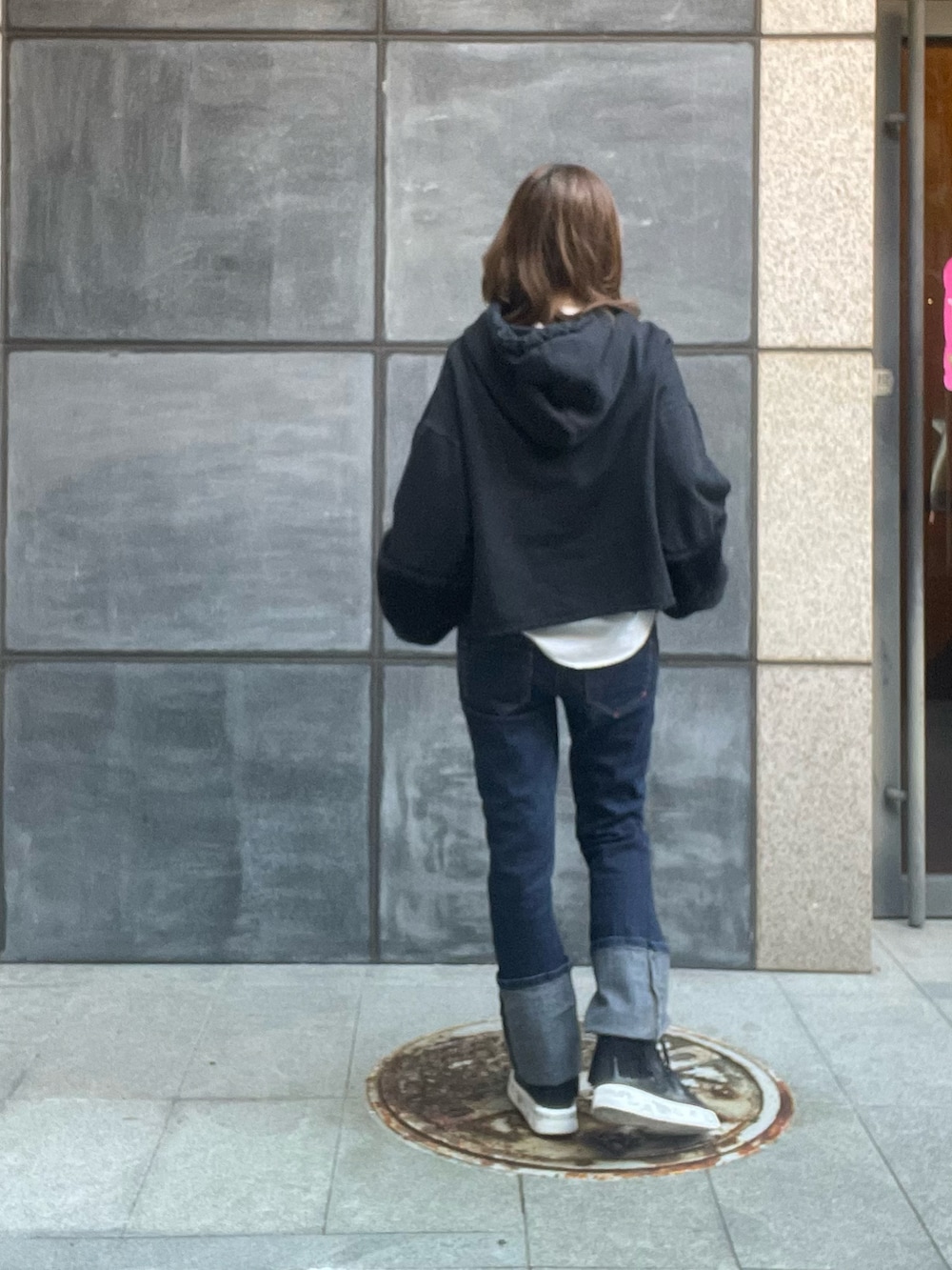 ブルー系のデニムパンツ、ブラック系のスニーカー、ブラック系のパーカーを着用したレディースの冬コーディネートの2枚目の写真