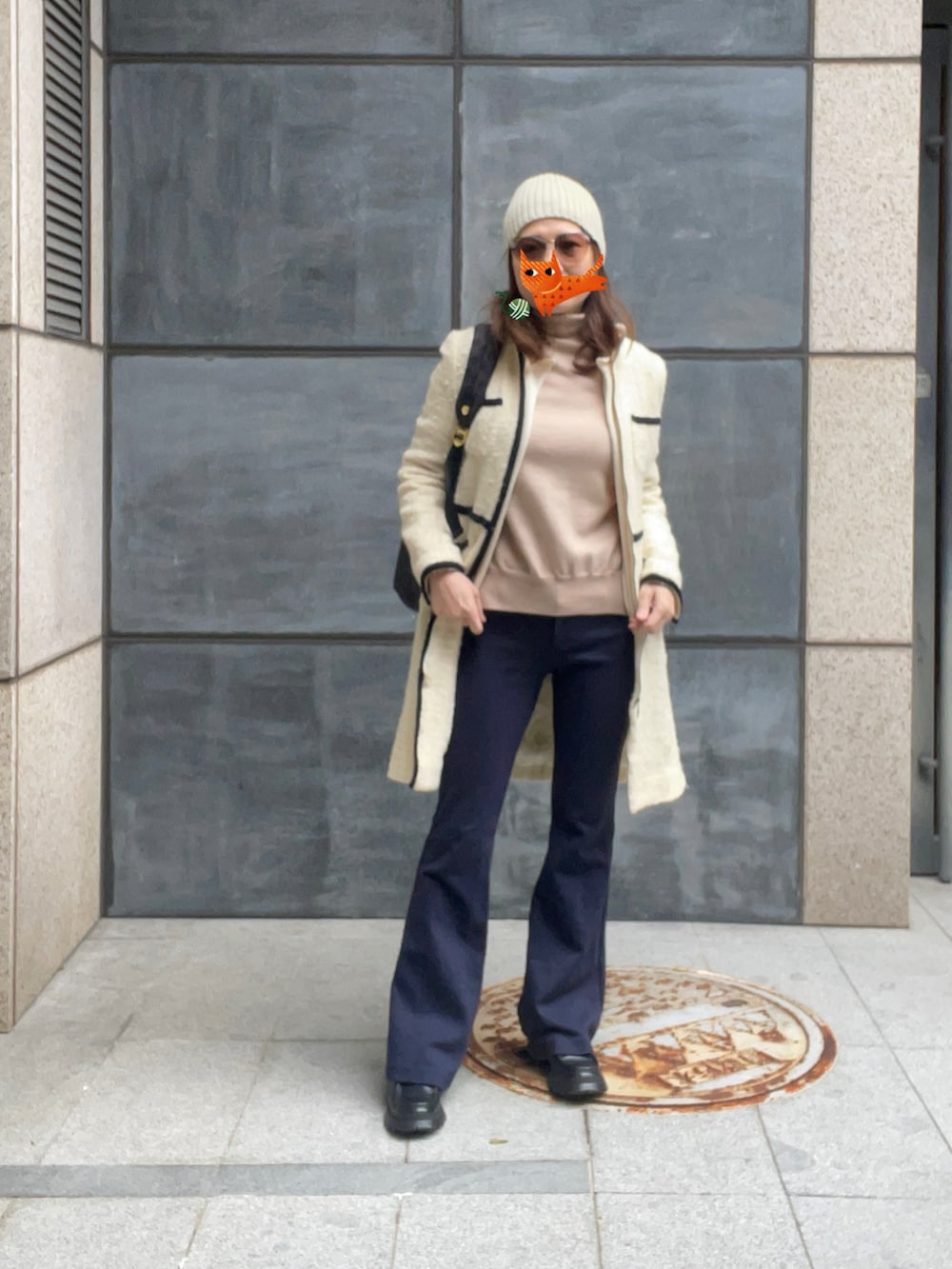 ベージュ系のニット/セーター、ブルー系のスラックス、ブラック系のブーツを着用したレディースの春コーディネートの2枚目の写真