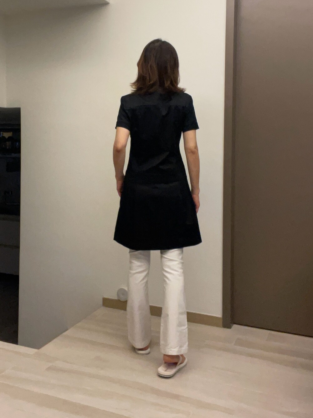 ブラック系のチュニック、ブラック系のスラックス、ホワイト系のデニムパンツを着用したレディースの春コーディネートの2枚目の写真