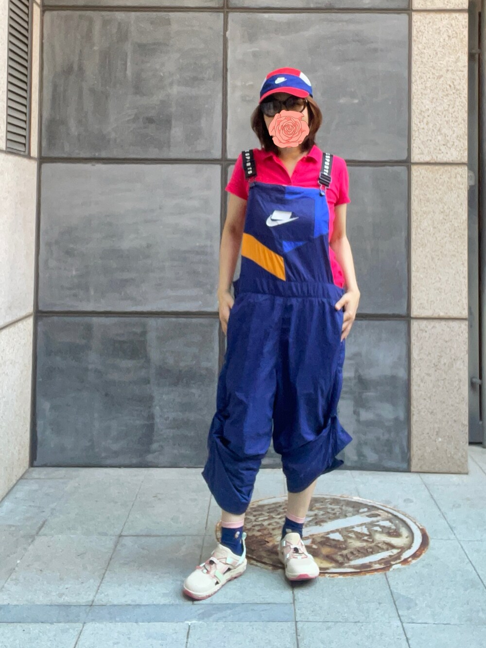 レッド系のポロシャツ、ブルー系のつなぎ/オールインワン、ベージュ系のレインシューズを着用したレディースの秋コーディネートの3枚目の写真