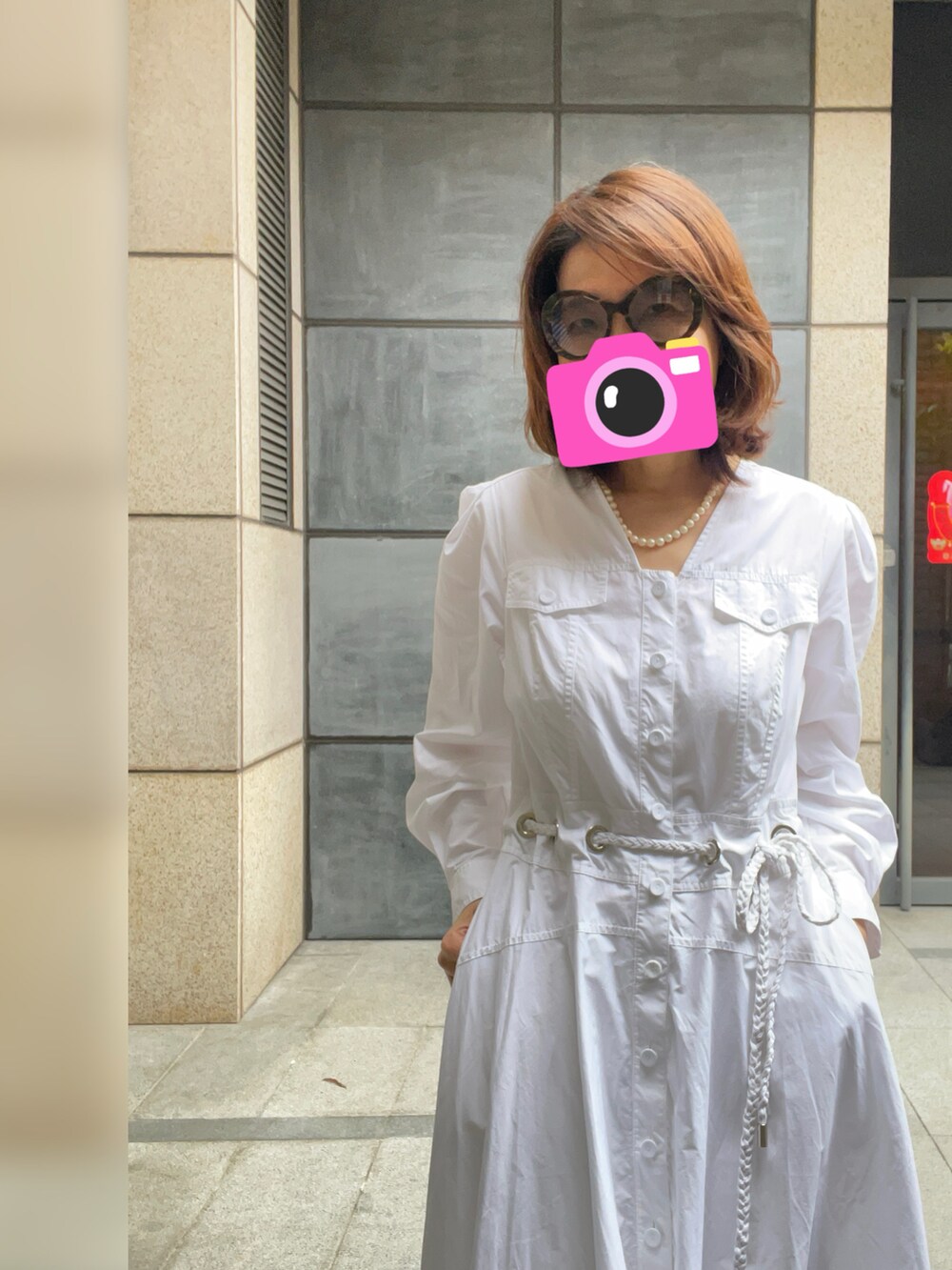 ベージュ系のスニーカー、ホワイト系のシャツワンピース、ブラウン系のサングラスを着用したレディースの春コーディネートの2枚目の写真