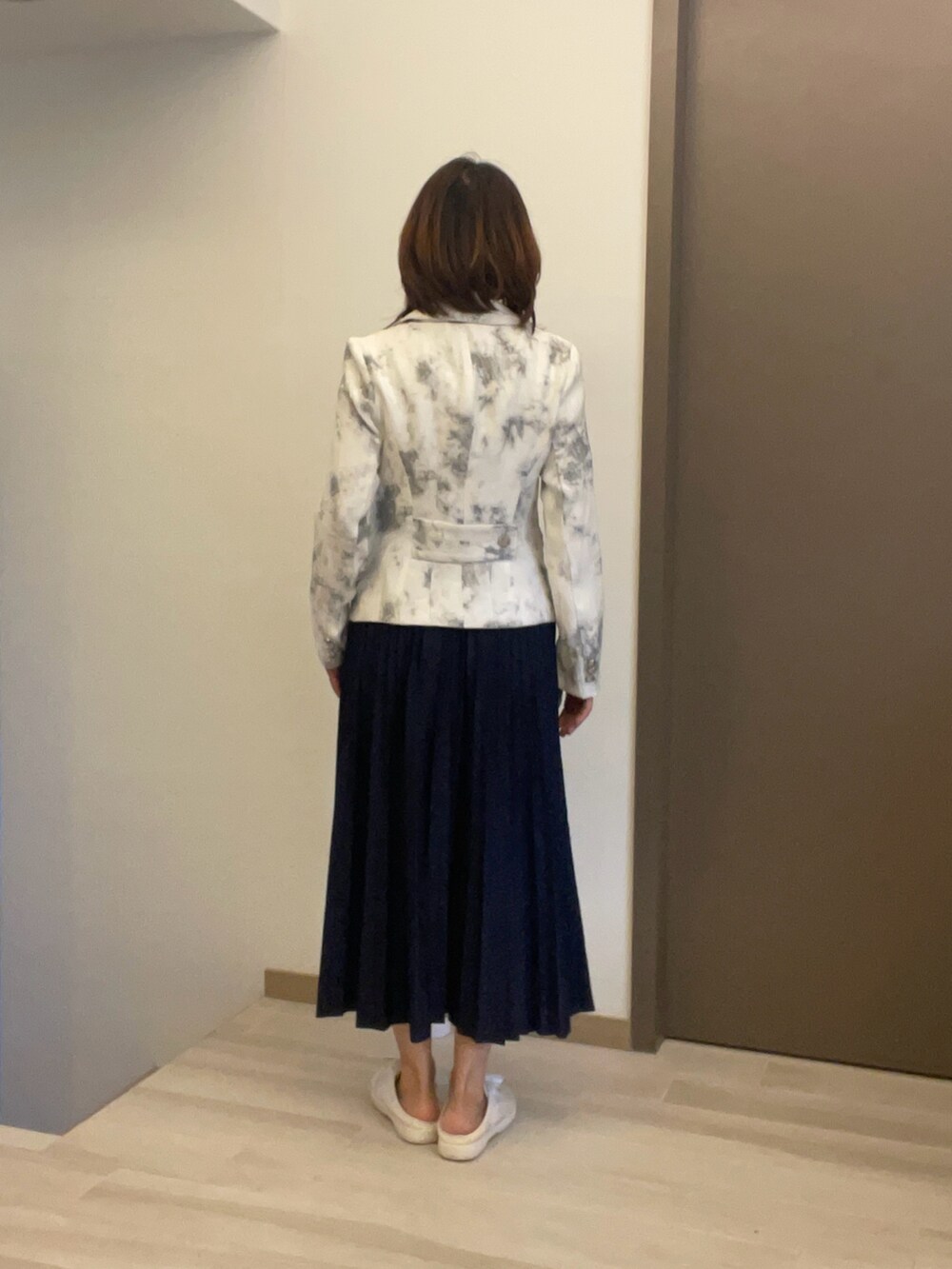 ベージュ系のビジネスシャツ、ホワイト系のテーラードジャケット、ブルー系のスカートを着用したレディースの秋コーディネートの3枚目の写真