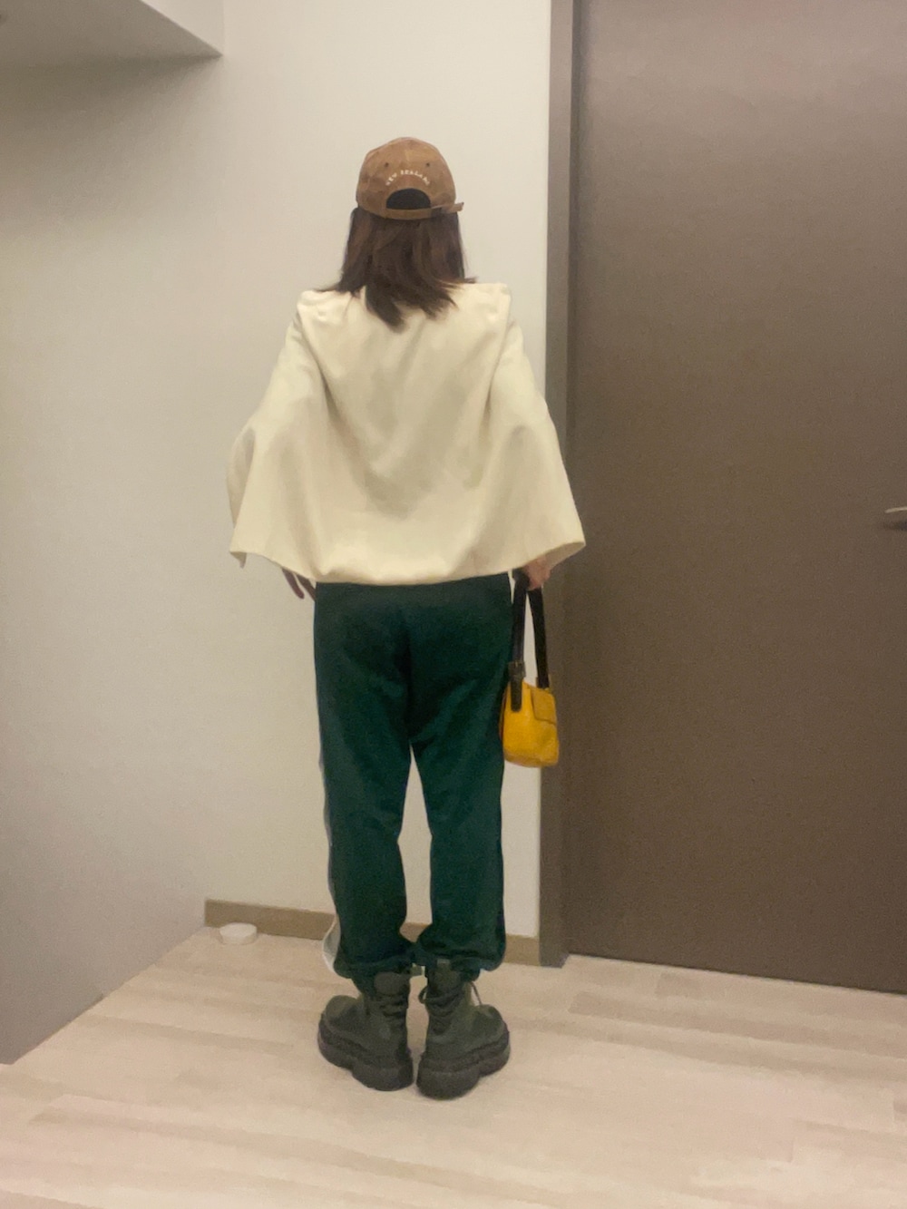 ベージュ系のステンカラーコート、グリーン系のチノパンツ、イエロー系のショルダーバッグを着用したレディースの春コーディネートの3枚目の写真