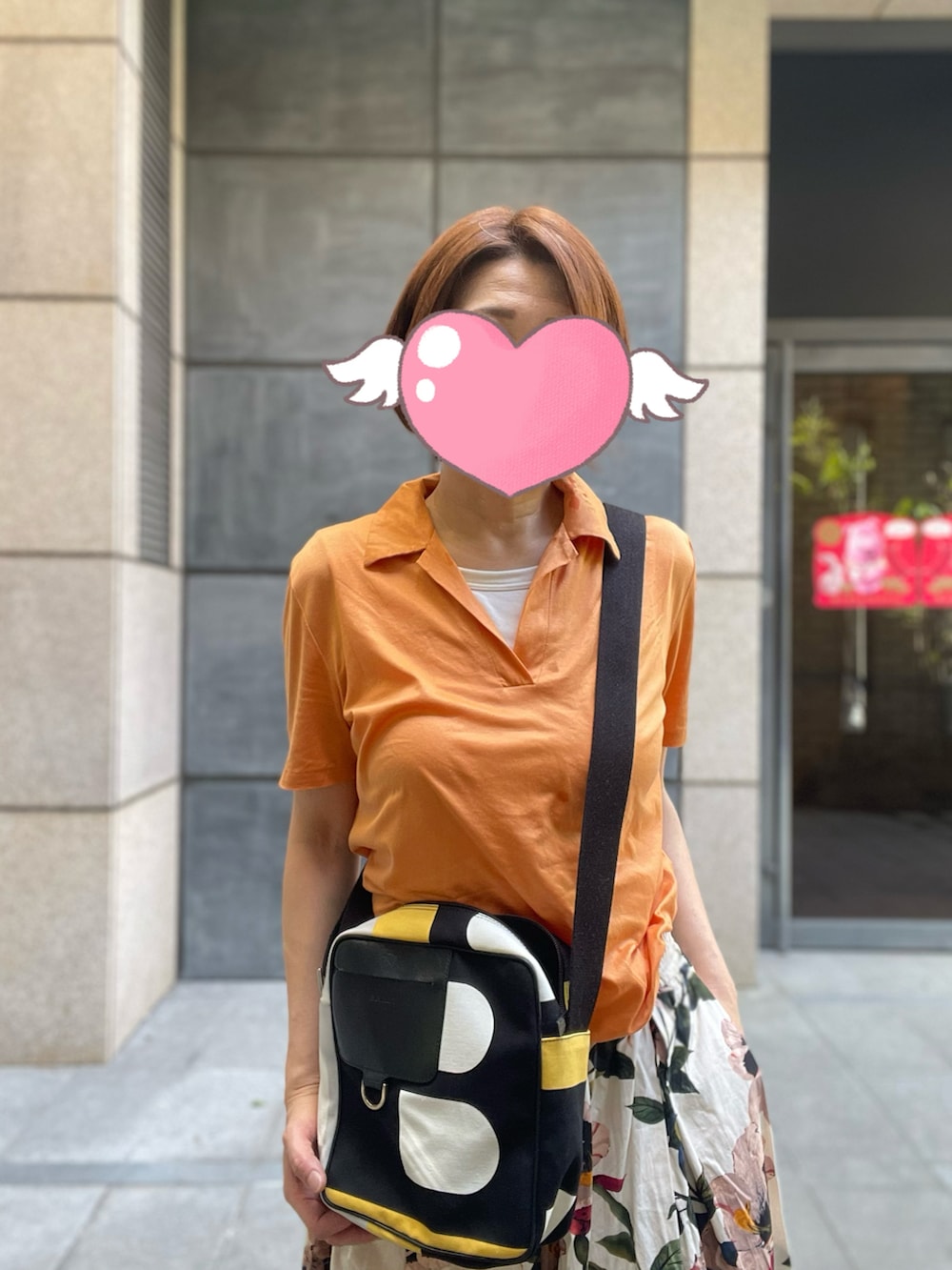 オレンジ系のTシャツ/カットソー、ブラック系のショルダーバッグ、ピンク系のスカートを着用したレディースの夏コーディネートの2枚目の写真