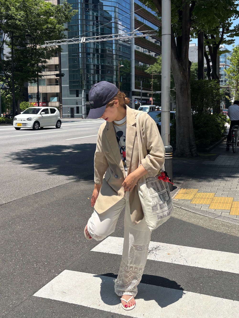 ベージュ系のテーラードジャケット、ホワイト系のその他パンツ、ブルー系のキャップを着用したレディースの夏コーディネートの3枚目の写真