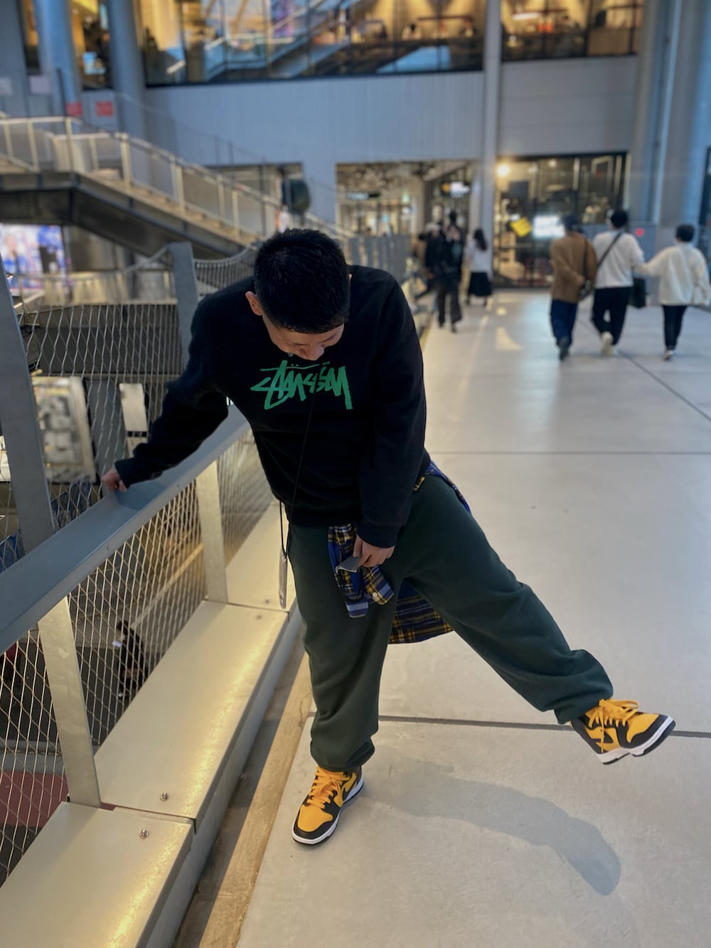 グリーン系のスウェット、グリーン系のスウェットパンツ、イエロー系のスニーカーを着用したメンズの秋コーディネートの2枚目の写真