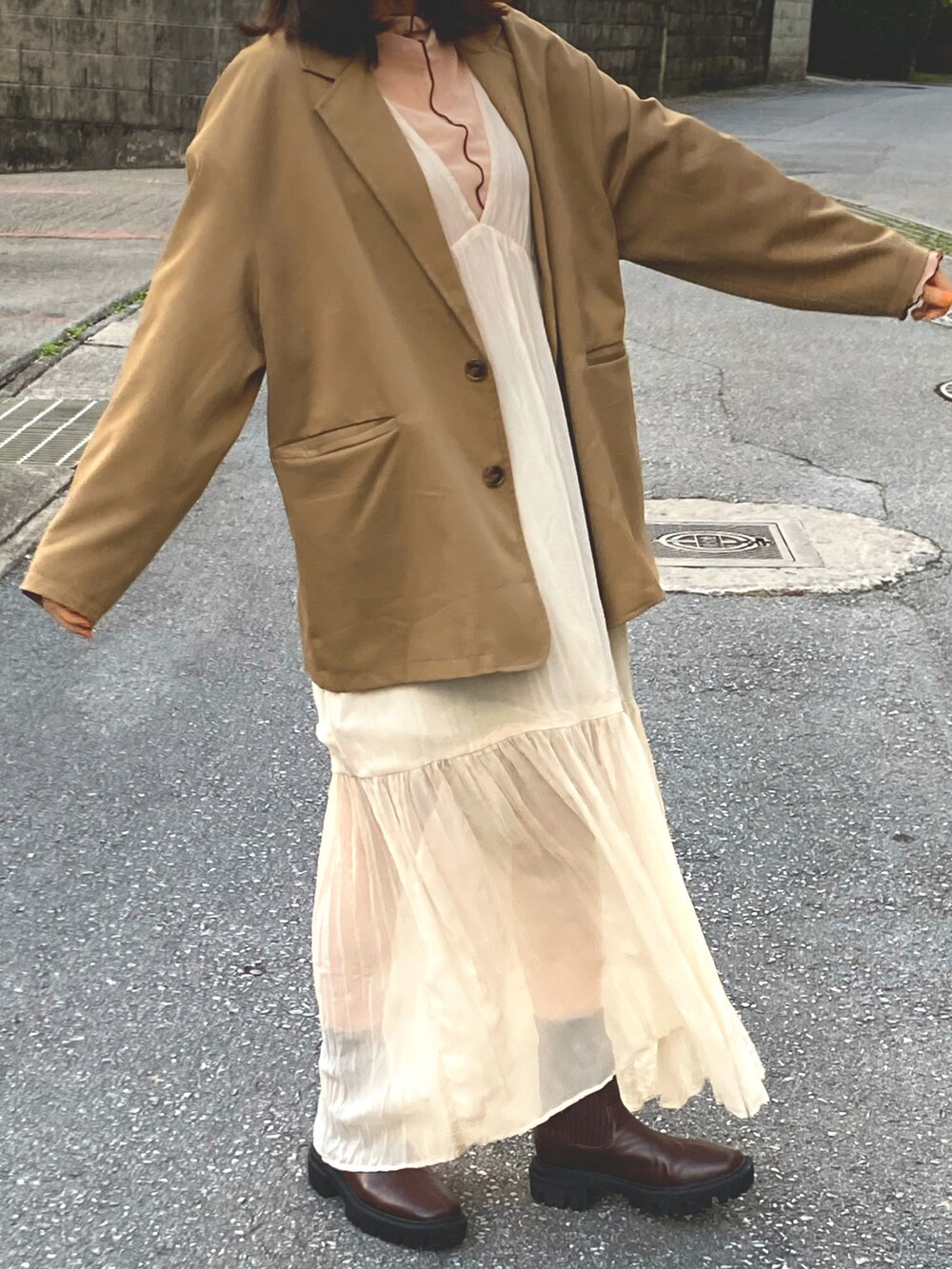 イエロー系のテーラードジャケット、ホワイト系のワンピース、ベージュ系のTシャツ/カットソーを着用したレディースの冬コーディネートの2枚目の写真