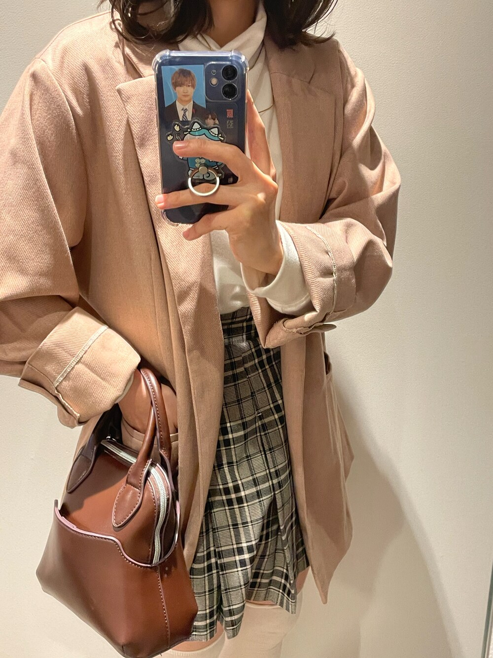 グレー系のスカート、ピンク系のテーラードジャケット、ブラウン系のハンドバッグを着用したレディースの春コーディネートの2枚目の写真