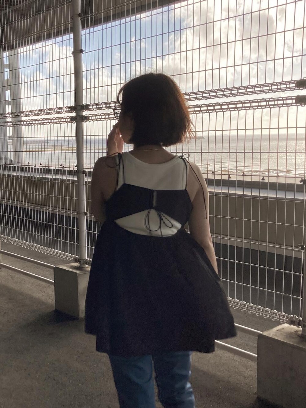 ブラック系のキャミソール、ベージュ系のタンクトップを着用したレディースの夏コーディネートの2枚目の写真