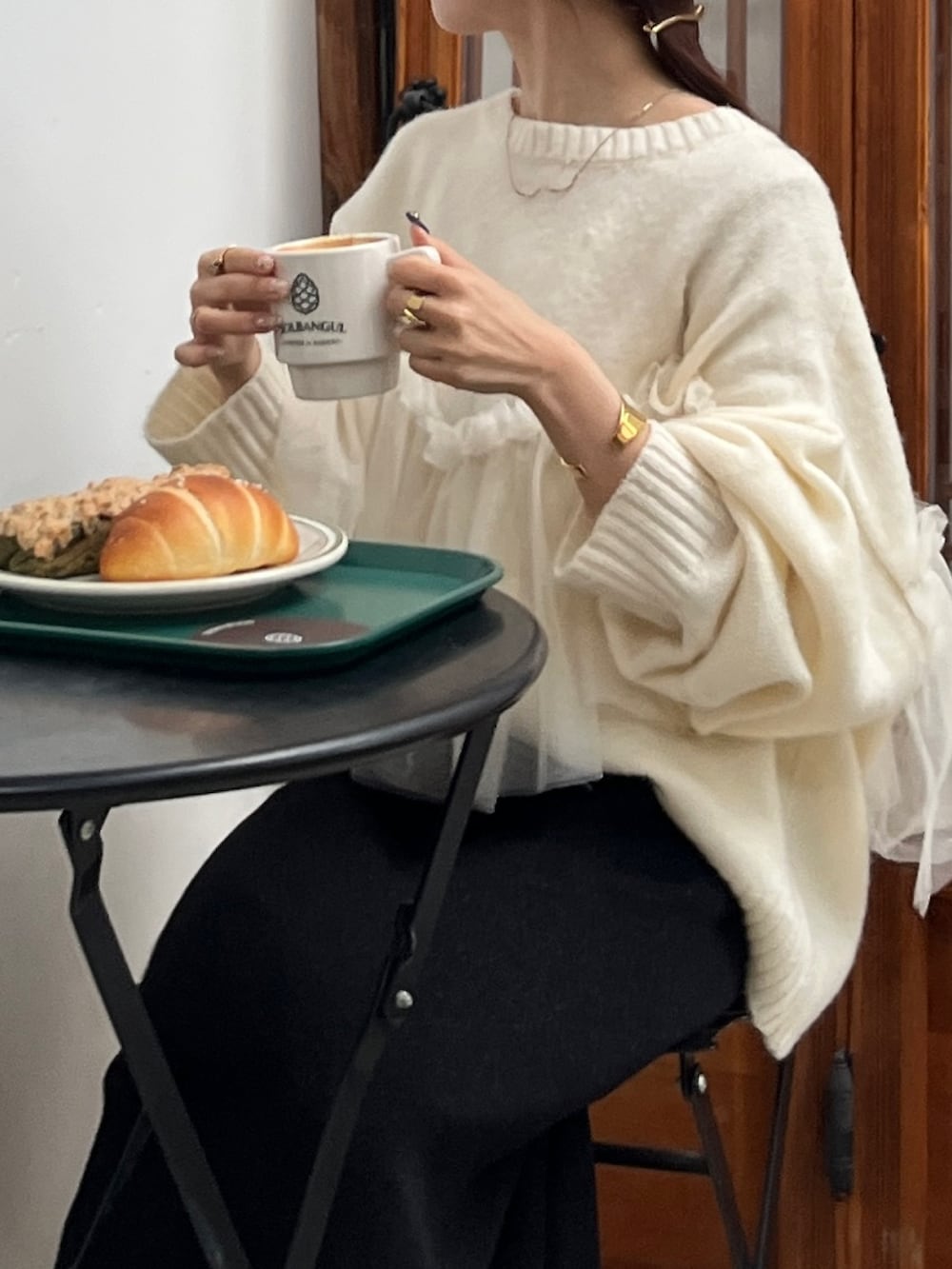 ホワイト系のニット/セーター、ブラック系のショルダーバッグ、ホワイト系のスニーカーを着用したレディースの冬コーディネートの2枚目の写真