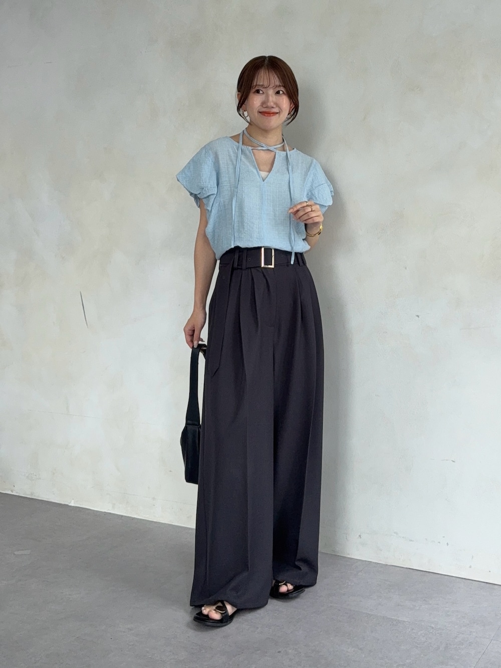 ブルー系のシャツ/ブラウス、グレー系のスラックス、ブラック系のサンダルを着用したレディースの夏コーディネートの2枚目の写真