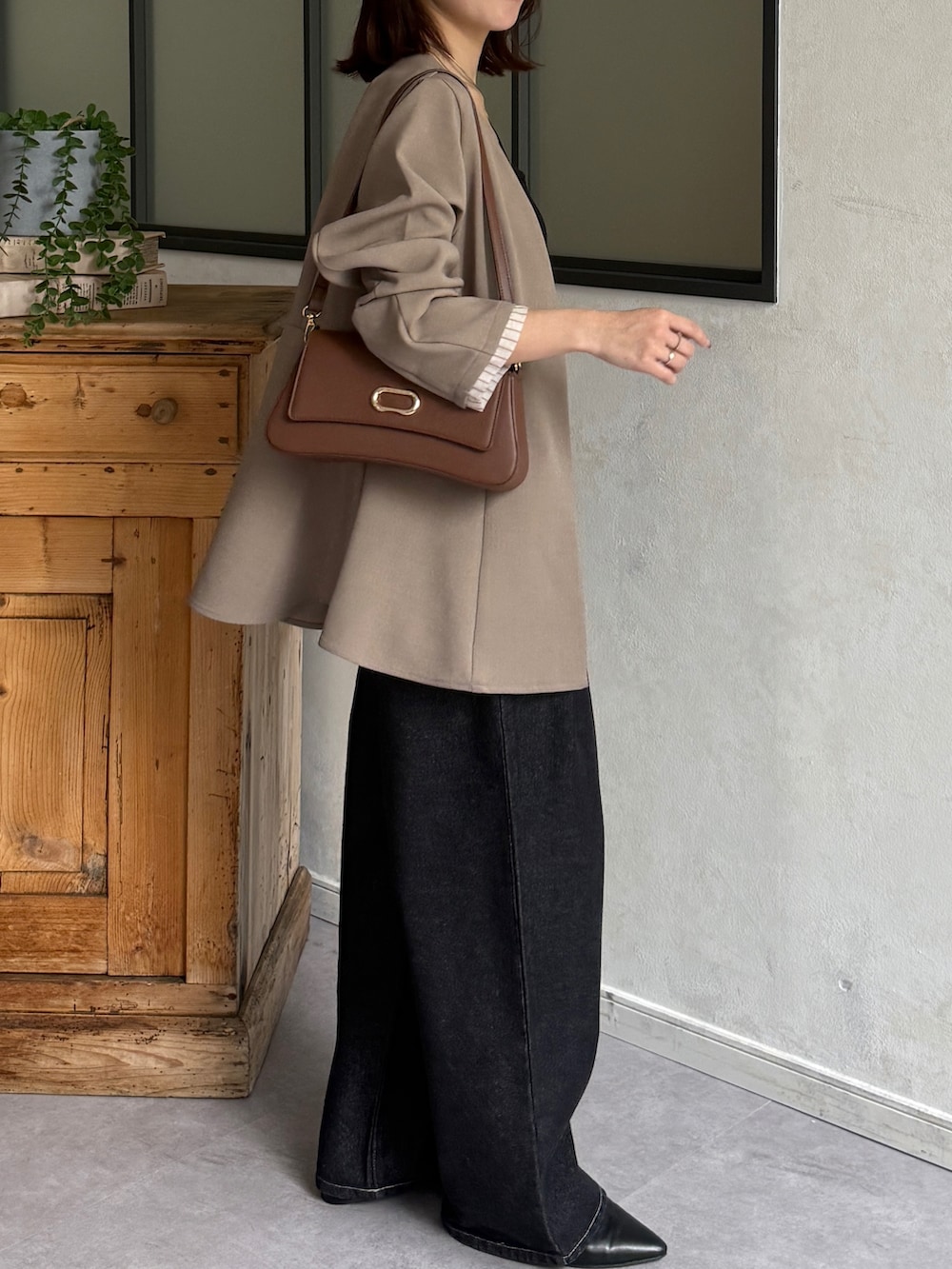 ベージュ系のテーラードジャケット、ブラック系のキャミソール、ブラック系のデニムパンツを着用したレディースの春コーディネートの2枚目の写真