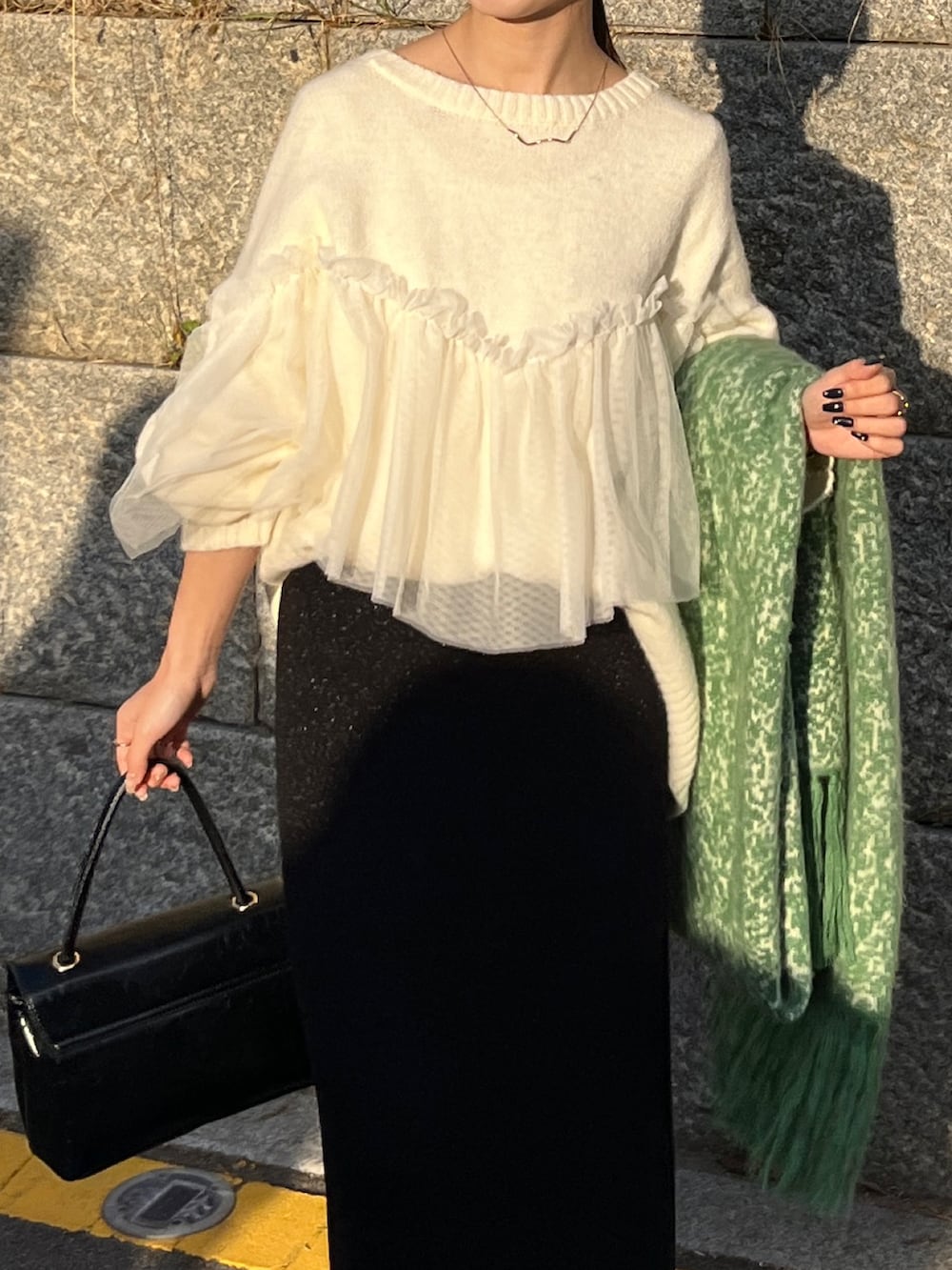 ホワイト系のニット/セーター、ブラック系のショルダーバッグ、ホワイト系のスニーカーを着用したレディースの冬コーディネートの3枚目の写真