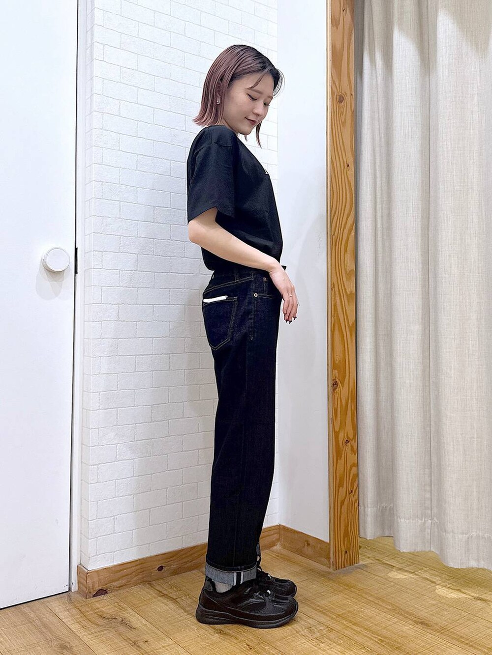 ブラック系のTシャツ/カットソー、ブルー系のデニムパンツ、グリーン系のボストンバッグを着用したレディースの春コーディネートの2枚目の写真