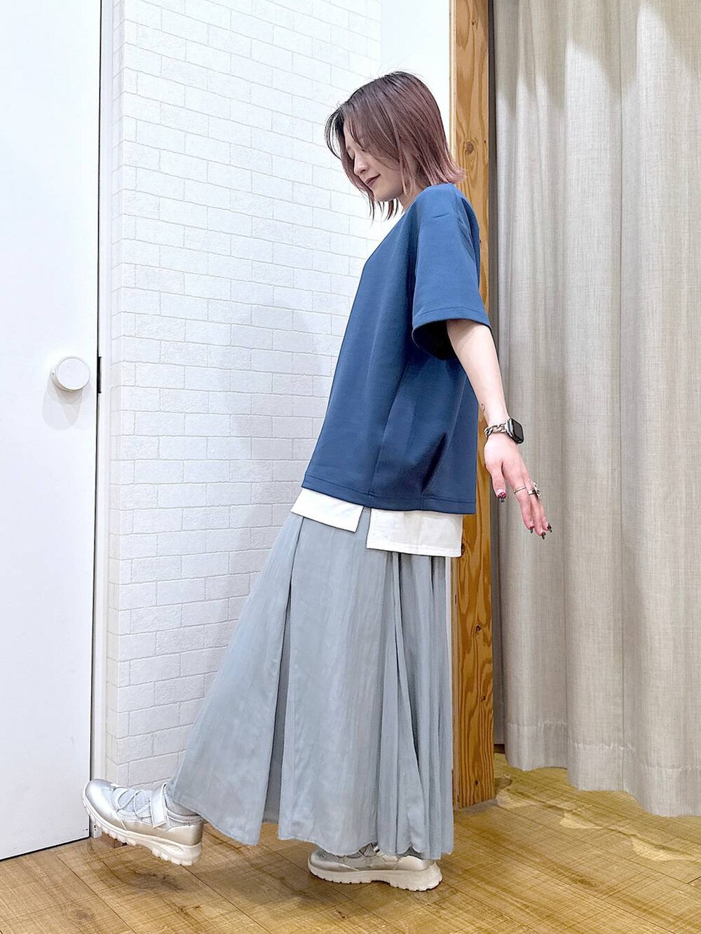 グリーン系のスカート、シルバー系のショルダーバッグ、グレー系のスニーカーを着用したレディースの春コーディネートの4枚目の写真