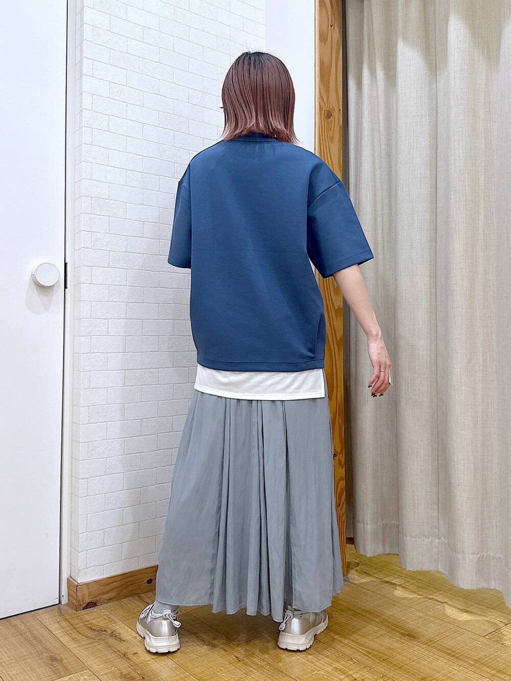 グリーン系のスカート、シルバー系のショルダーバッグ、グレー系のスニーカーを着用したレディースの春コーディネートの3枚目の写真