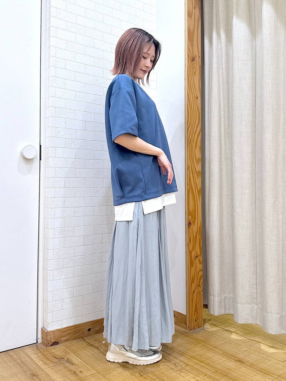 グリーン系のスカート、シルバー系のショルダーバッグ、グレー系のスニーカーを着用したレディースの春コーディネートの2枚目の写真