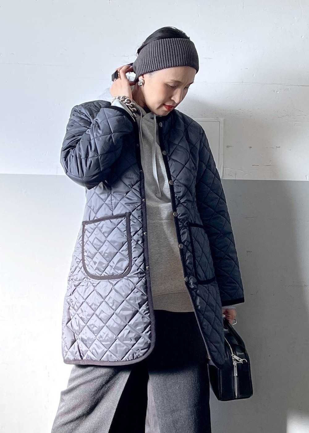 ブラック系のショルダーバッグ、ブラック系のスカート、ホワイト系のスニーカーを着用したレディースの冬コーディネートの5枚目の写真