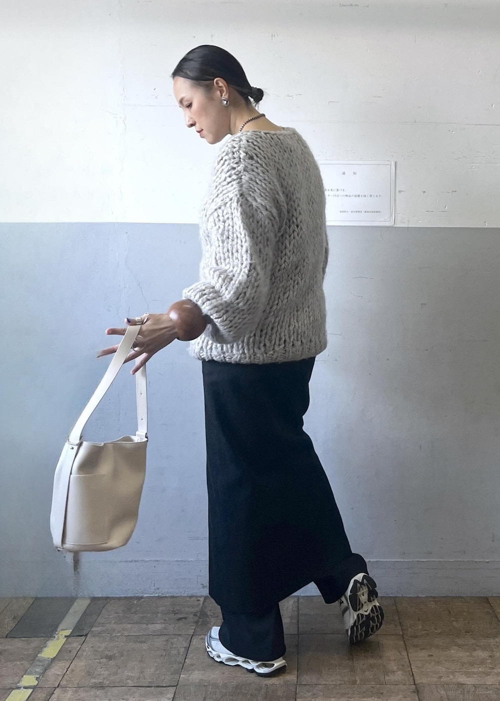 ブラック系のスカート、ホワイト系のショルダーバッグ、ホワイト系のスニーカーを着用したレディースの冬コーディネートの5枚目の写真