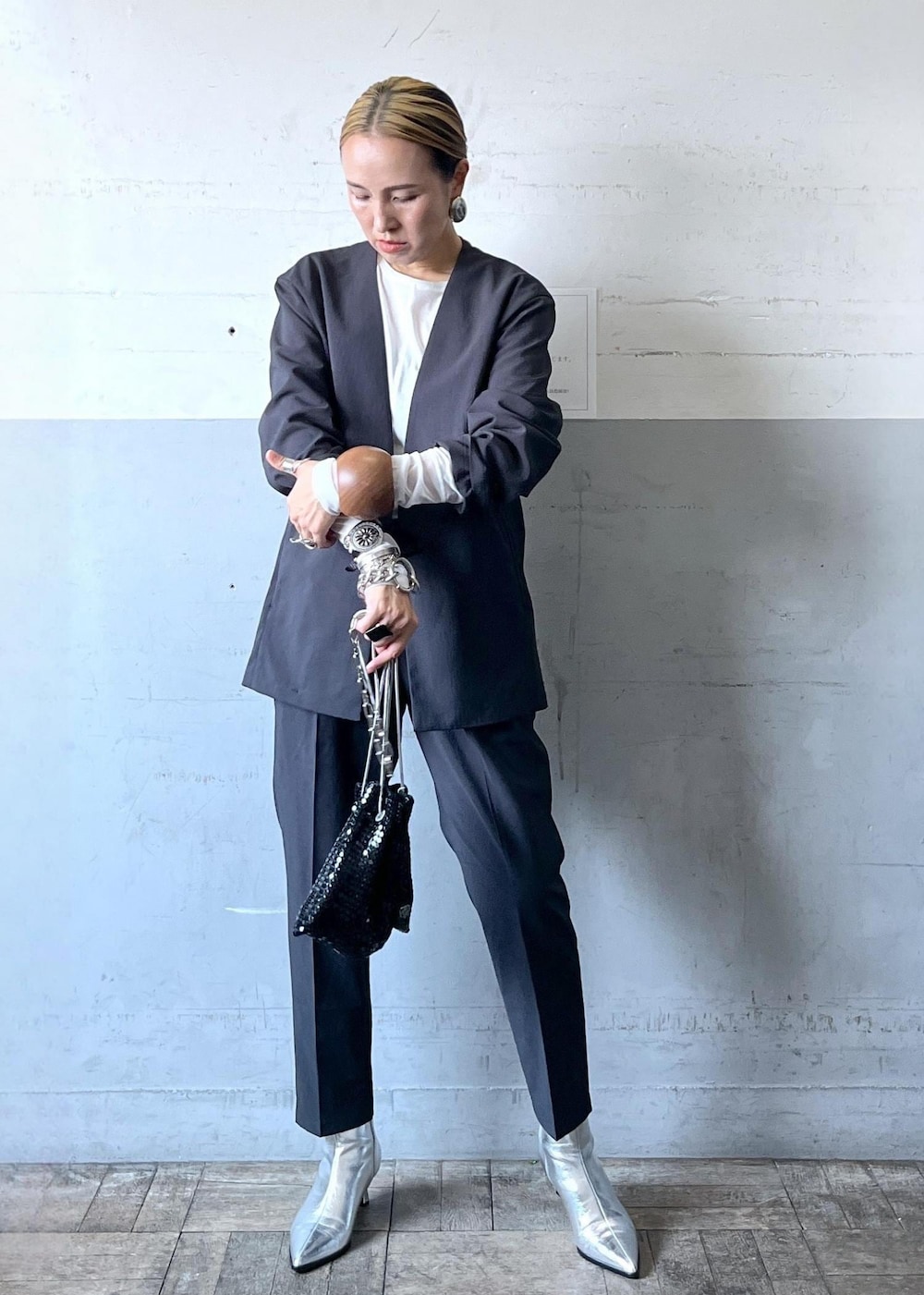 ブラック系のハンドバッグ、ブラック系のセットアップ、シルバー系のブーツを着用したレディースの秋コーディネートの10枚目の写真