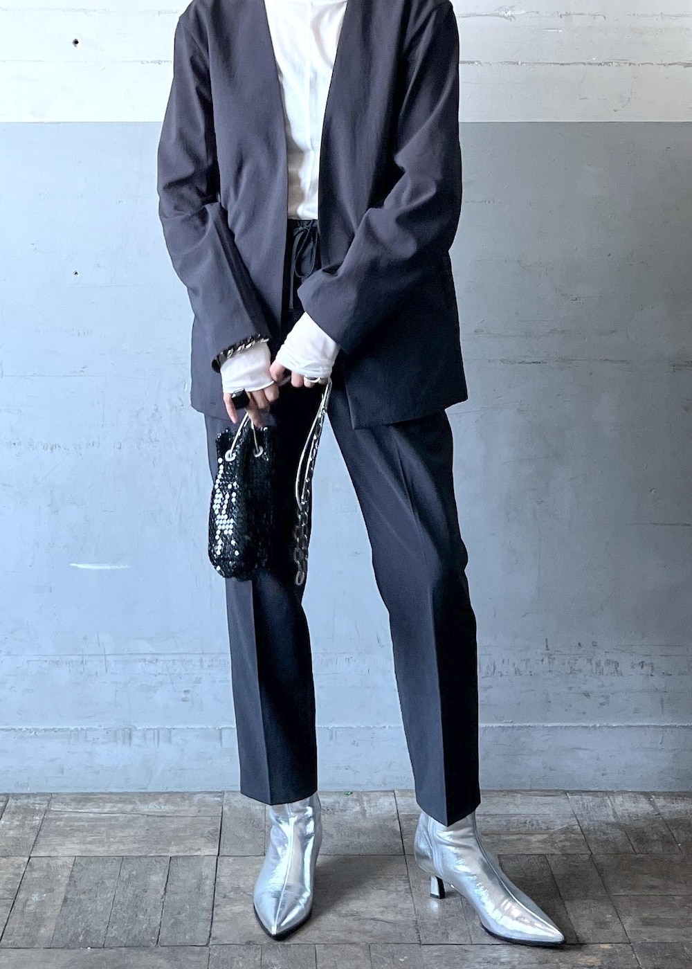 ブラック系のハンドバッグ、ブラック系のセットアップ、シルバー系のブーツを着用したレディースの秋コーディネートの3枚目の写真