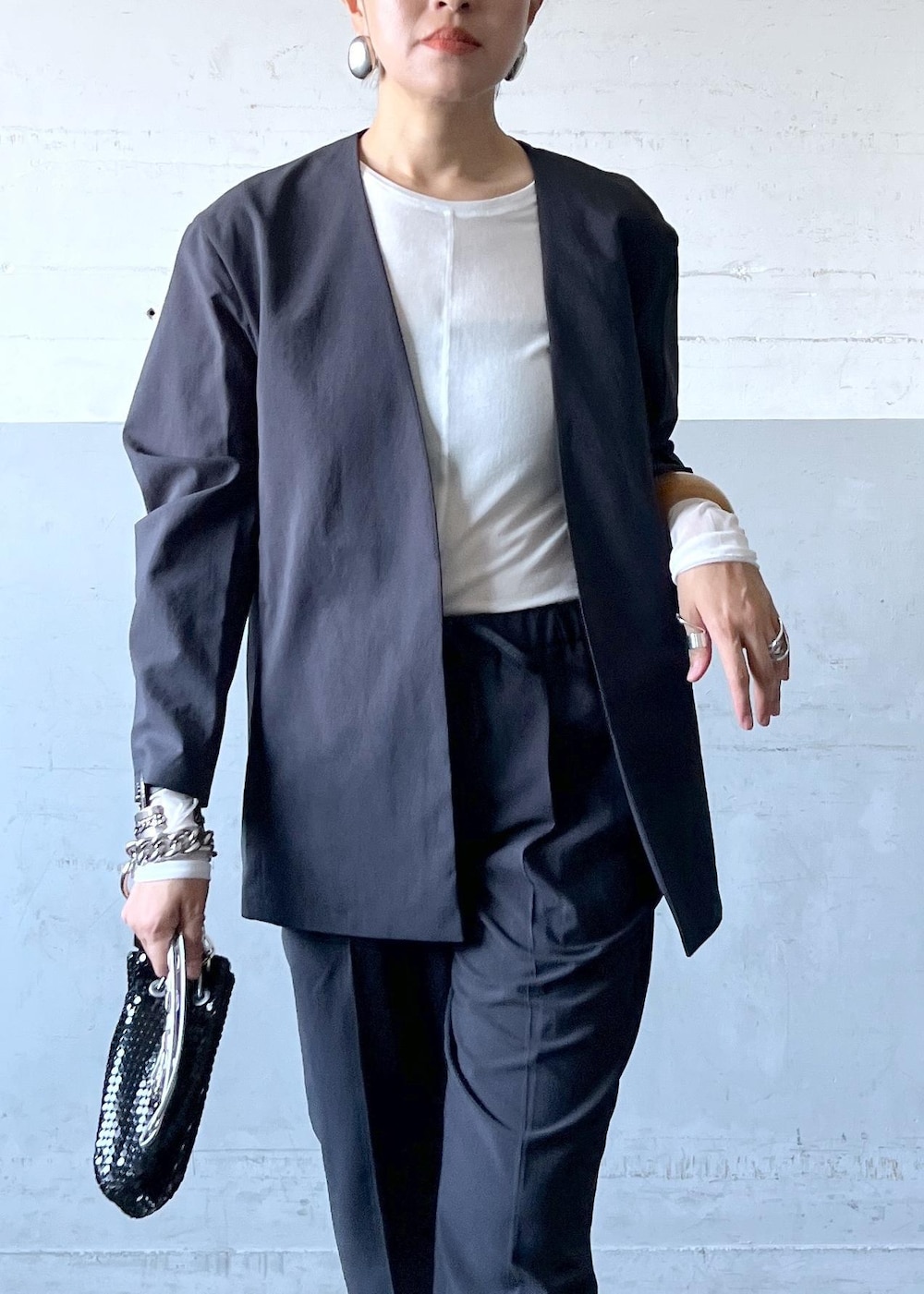 ブラック系のハンドバッグ、ブラック系のセットアップ、シルバー系のブーツを着用したレディースの秋コーディネートの6枚目の写真