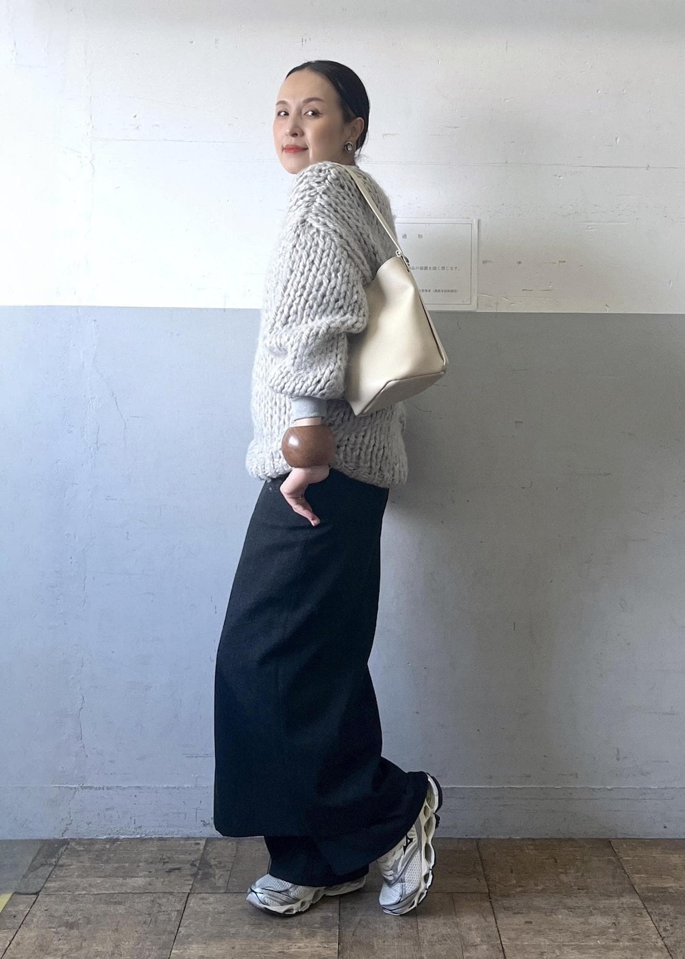 ブラック系のスカート、ホワイト系のショルダーバッグ、ホワイト系のスニーカーを着用したレディースの冬コーディネートの2枚目の写真