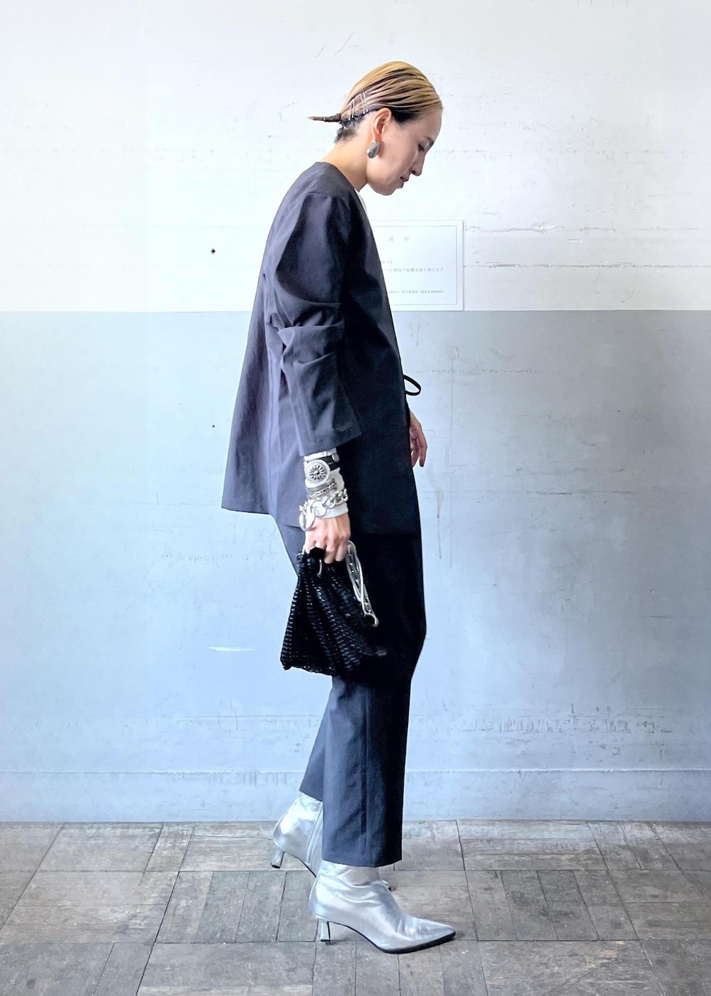 ブラック系のハンドバッグ、ブラック系のセットアップ、シルバー系のブーツを着用したレディースの秋コーディネートの5枚目の写真