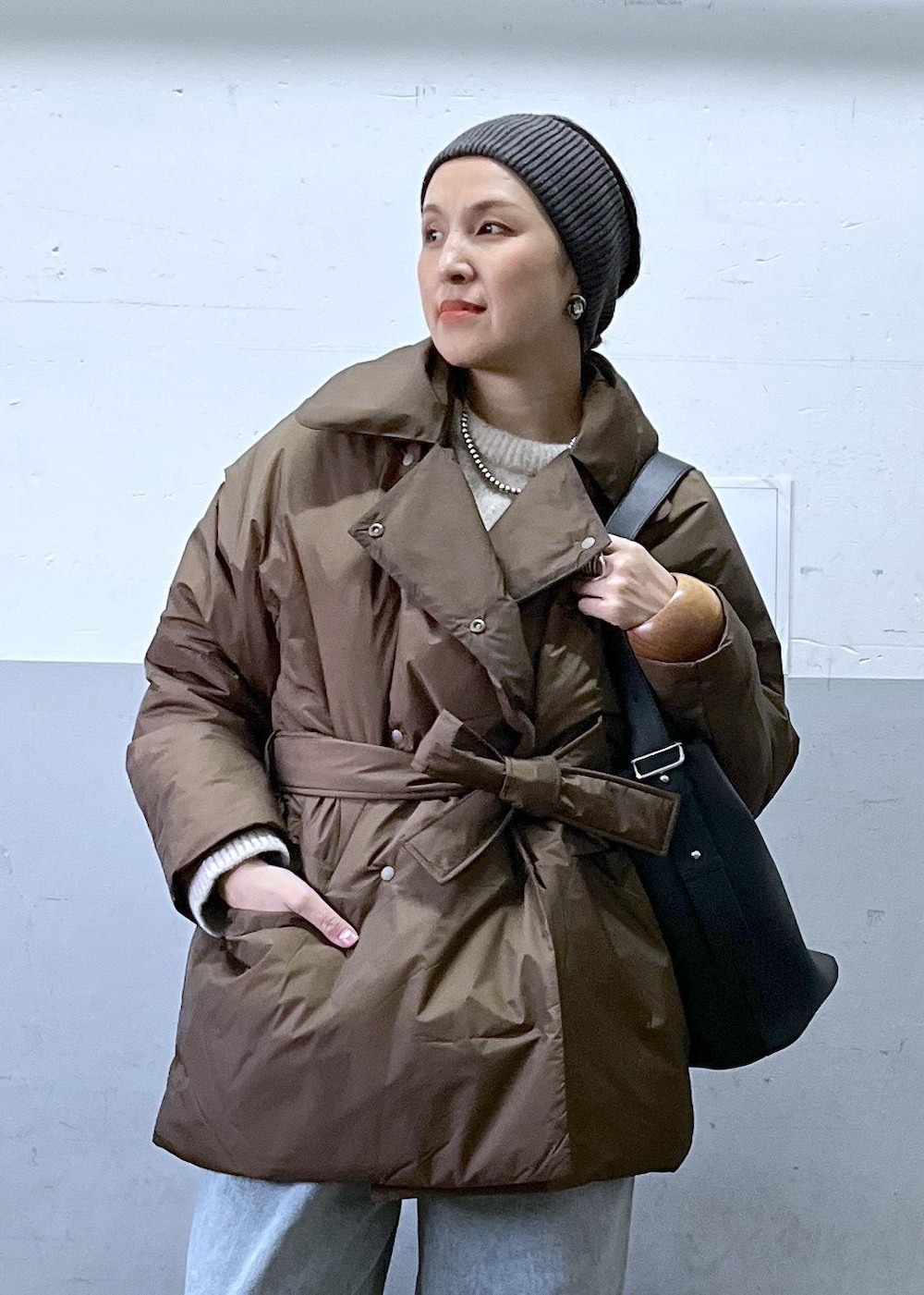 ブルー系のデニムパンツ、ブラック系のショルダーバッグ、ベージュ系のニット/セーターを着用したレディースの冬コーディネートの4枚目の写真