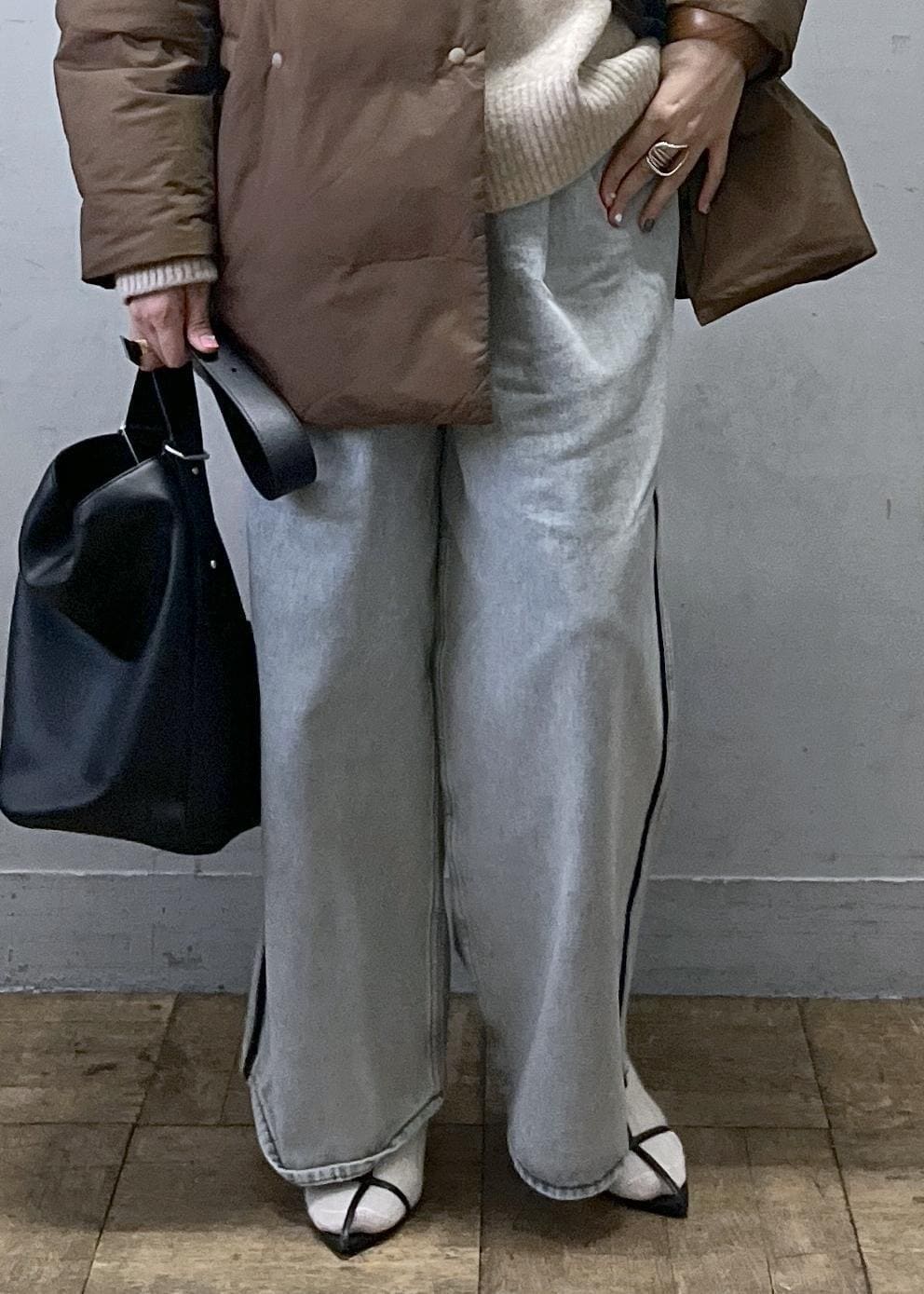 ブルー系のデニムパンツ、ブラック系のショルダーバッグ、ベージュ系のニット/セーターを着用したレディースの冬コーディネートの5枚目の写真