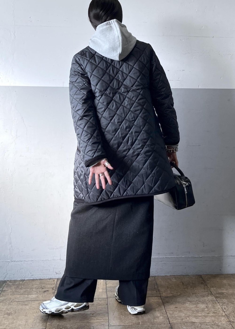 ブラック系のショルダーバッグ、ブラック系のスカート、ホワイト系のスニーカーを着用したレディースの冬コーディネートの6枚目の写真