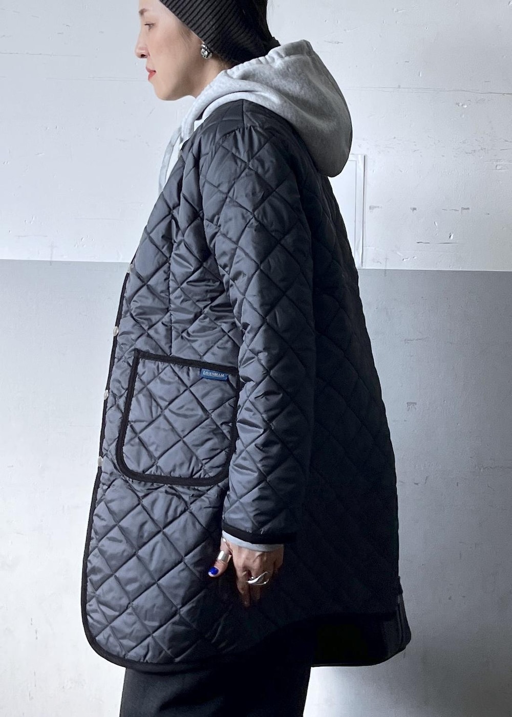 ブラック系のショルダーバッグ、ブラック系のスカート、ホワイト系のスニーカーを着用したレディースの冬コーディネートの7枚目の写真