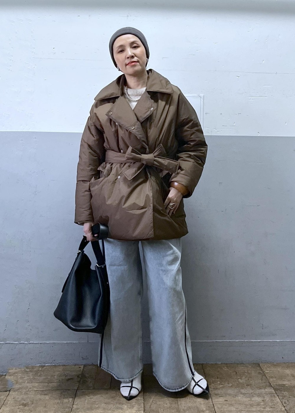 ブルー系のデニムパンツ、ブラック系のショルダーバッグ、ベージュ系のニット/セーターを着用したレディースの冬コーディネートの3枚目の写真