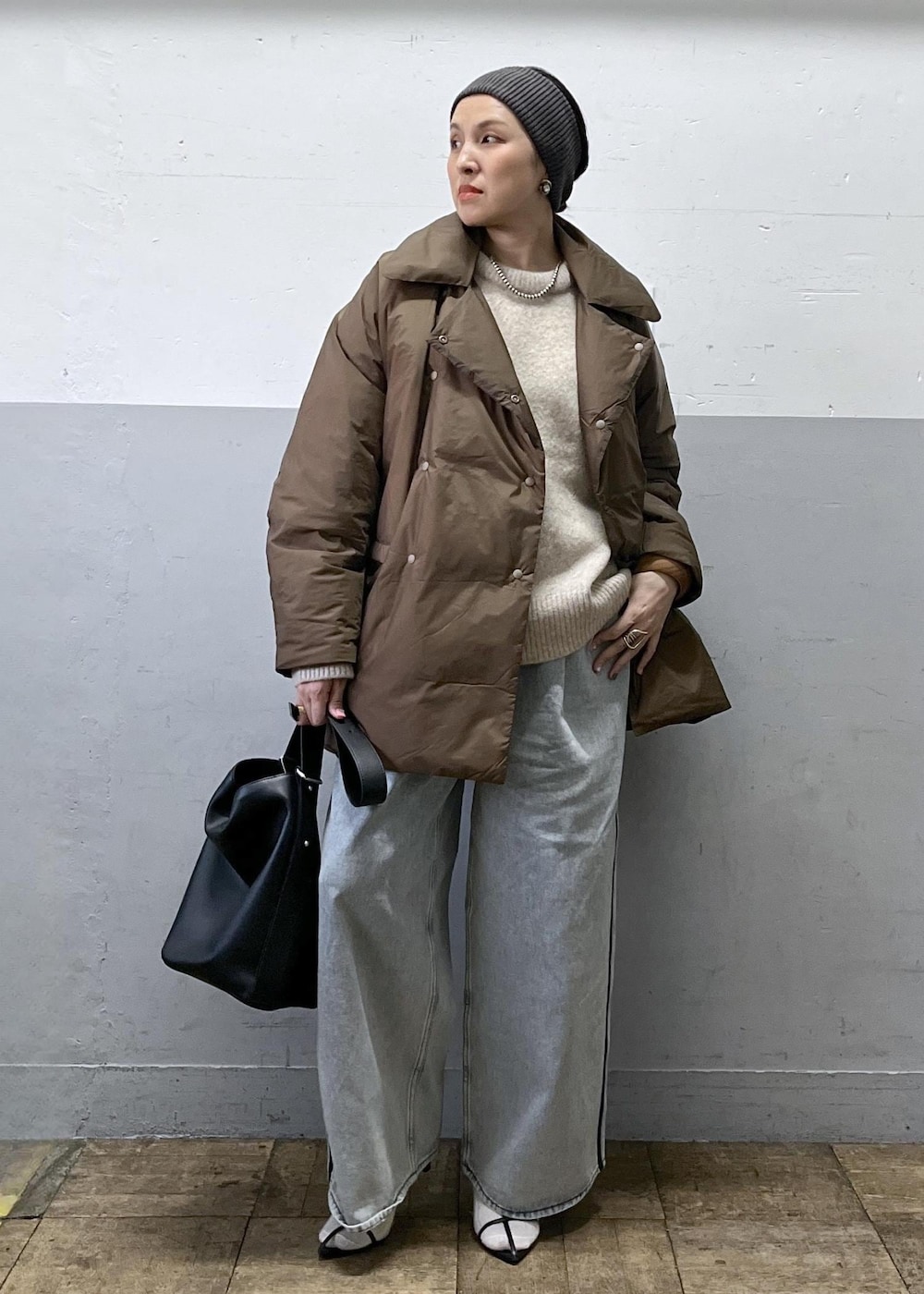 ブルー系のデニムパンツ、ブラック系のショルダーバッグ、ベージュ系のニット/セーターを着用したレディースの冬コーディネートの7枚目の写真