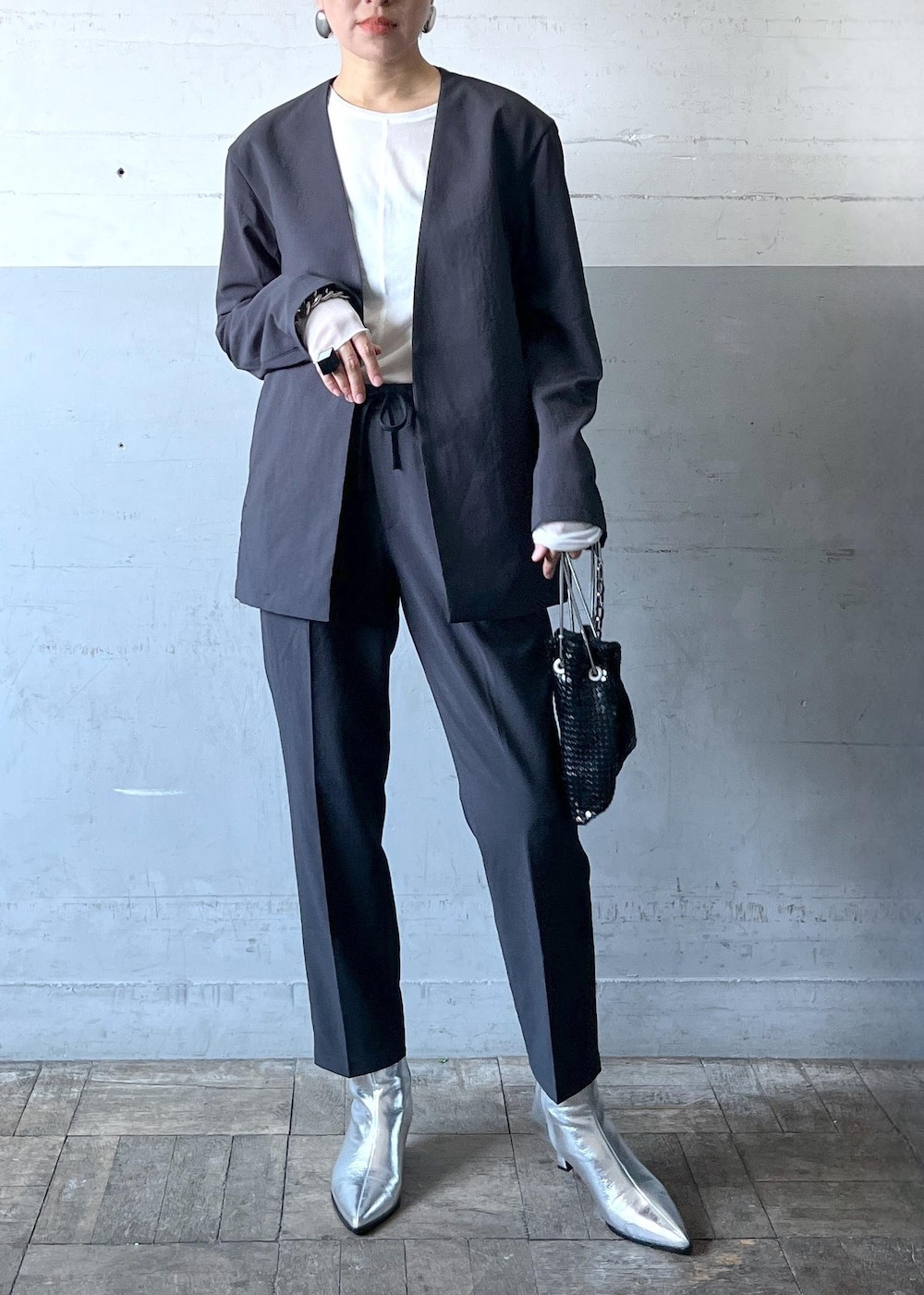 ブラック系のハンドバッグ、ブラック系のセットアップ、シルバー系のブーツを着用したレディースの秋コーディネートの2枚目の写真