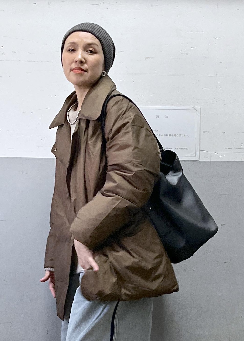 ブルー系のデニムパンツ、ブラック系のショルダーバッグ、ベージュ系のニット/セーターを着用したレディースの冬コーディネートの8枚目の写真