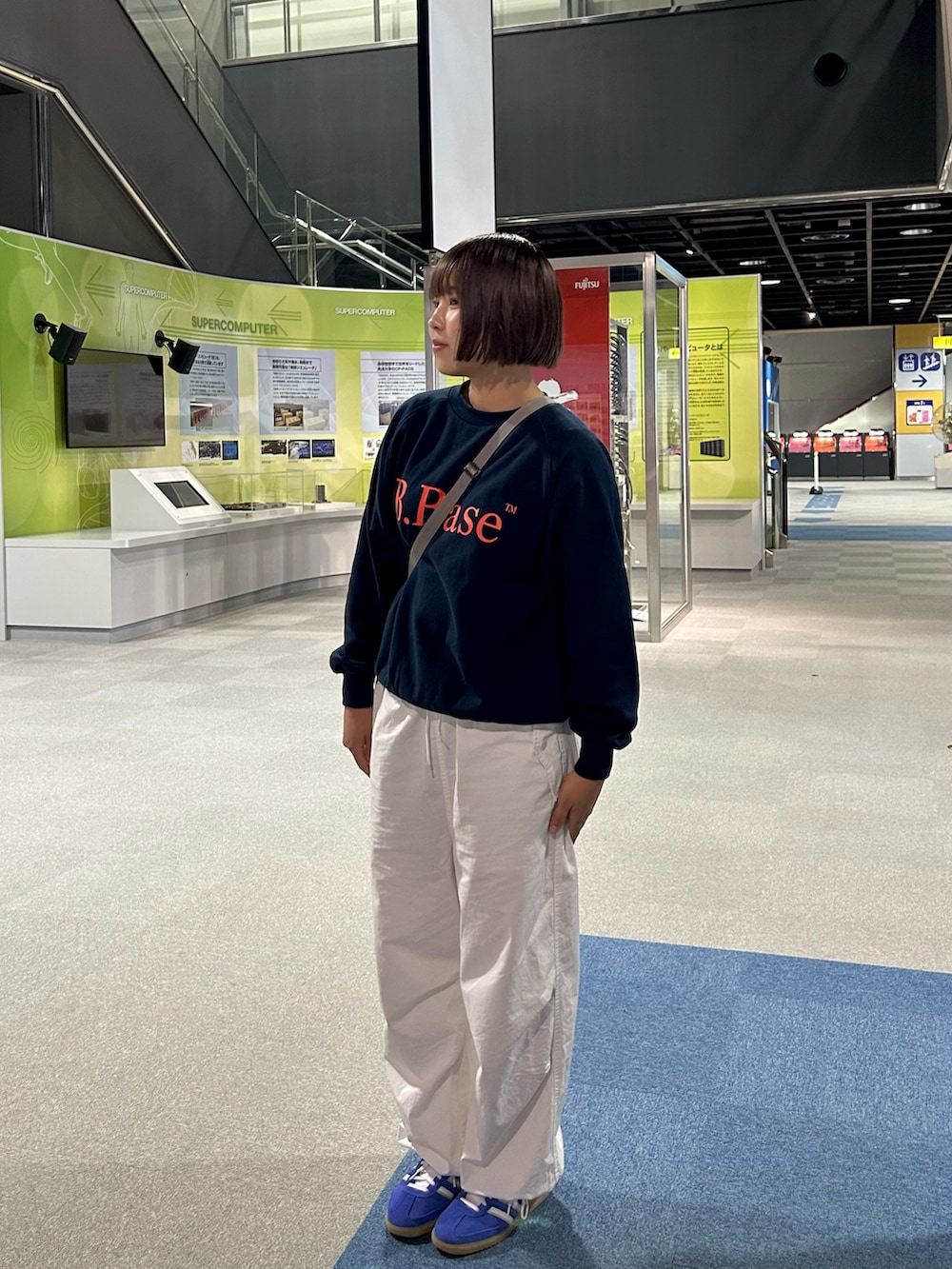 ホワイト系のカーゴパンツ、ブルー系のスニーカー、グレー系のショルダーバッグを着用したレディースの秋コーディネートの2枚目の写真