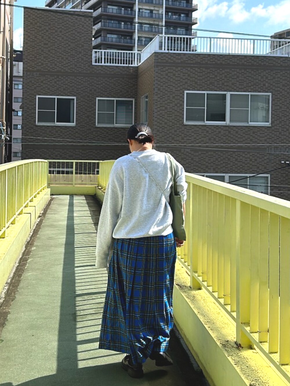 ブルー系のスカート、グレー系のスウェット、グリーン系のトートバッグを着用したレディースの秋コーディネートの2枚目の写真